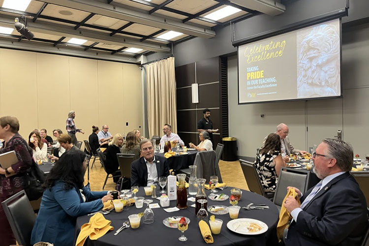 Professors and members of PNW's leadership sit at large, round tables.