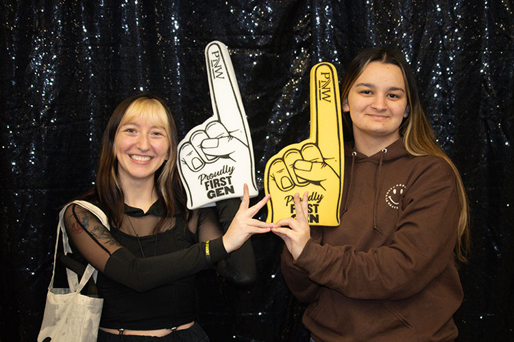 Two students stand together with "First-Gen" foam fingers