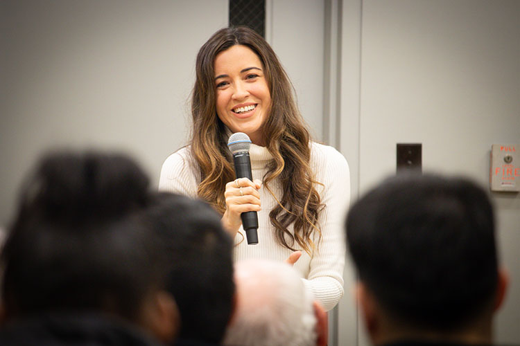 Alejandra Campoverdi stands with a microphone in hand as she speaks to first-generation students.