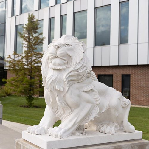 A white stone lion statue in front of the Nils Building on the PNW Hammond Campus
