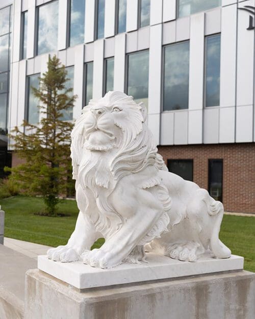 A white stone lion statue in front of the Nils Building on the PNW Hammond Campus