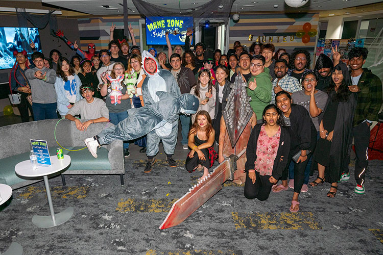 A large group of costumed and casual PNW students pose for picture in celebration for Halloween at the Mane Zone Fright Night.