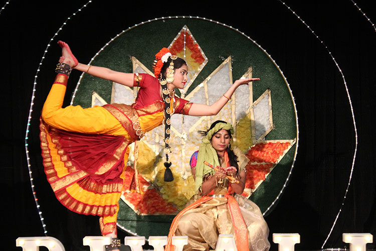 Two women dressed in traditional Indian garb perform for Dwali.