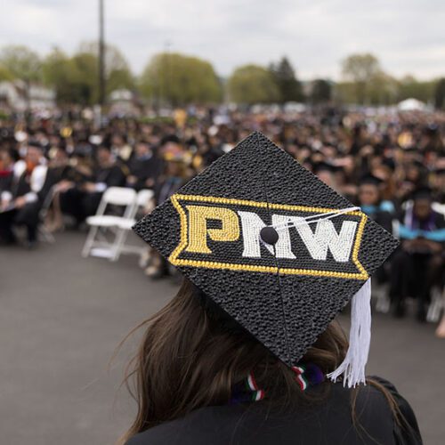 A student with a PNW branded mortarboard marches at commencement