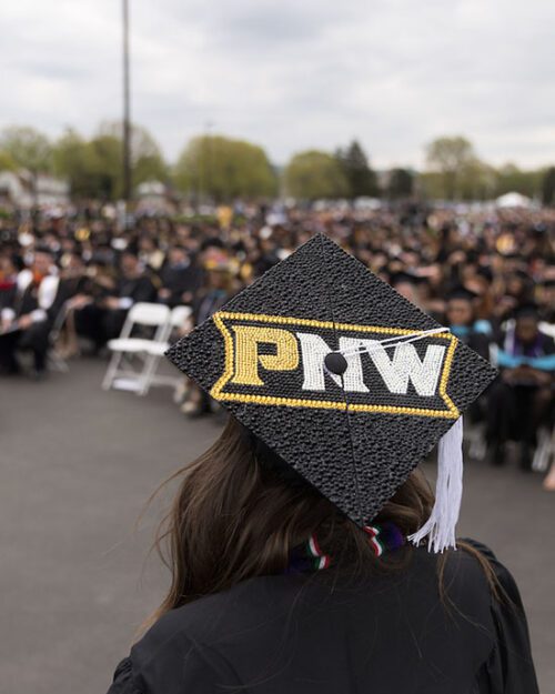 A student with a PNW branded mortarboard marches at commencement