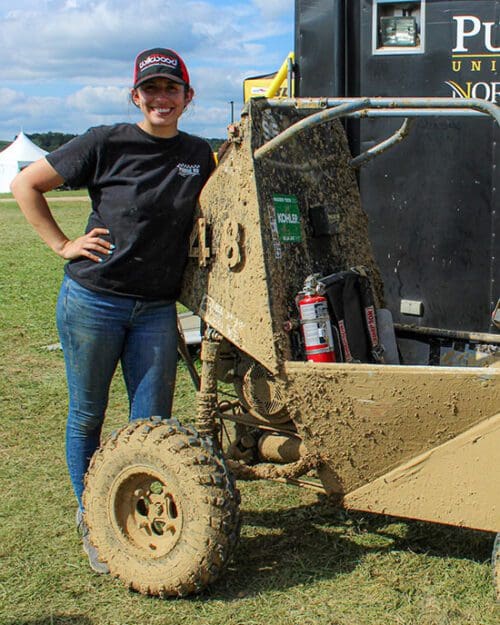 Mia Flory leans against the outside of a race car.