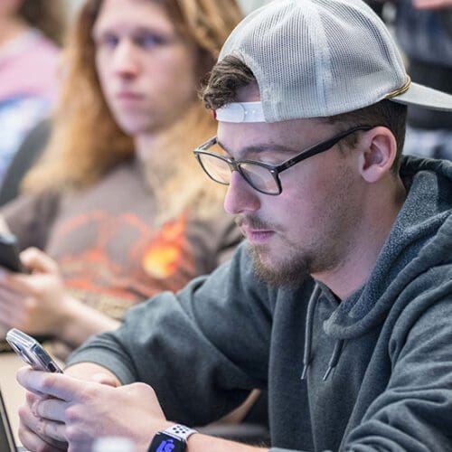 A PNW student checks his phone in the classroom