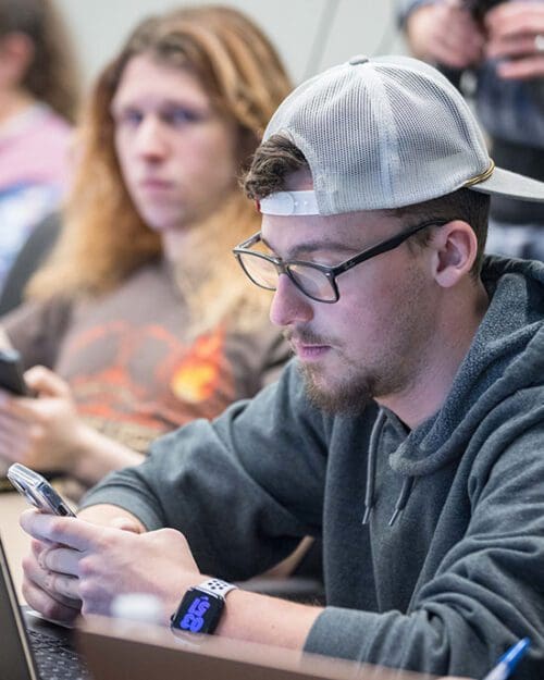 A PNW student checks his phone in the classroom