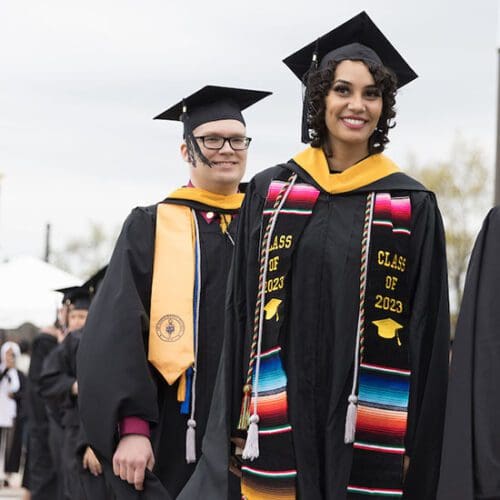 PNW students pose in graduation regalia including silver cords signifying their first-gen status.