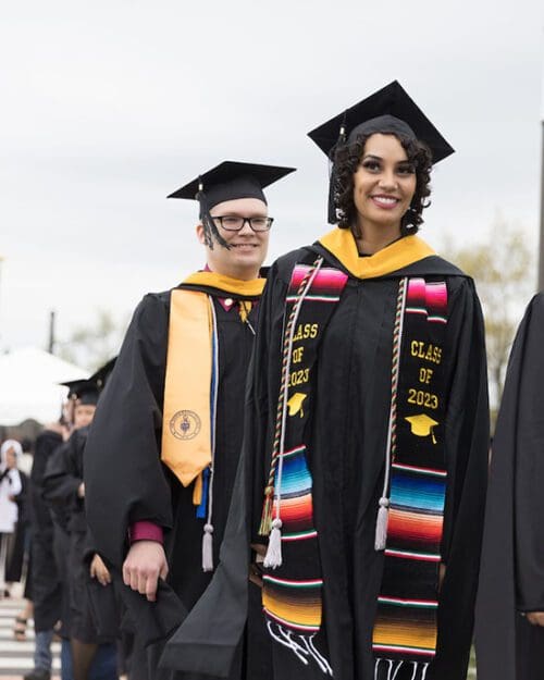 PNW students pose in graduation regalia including silver cords signifying their first-gen status.