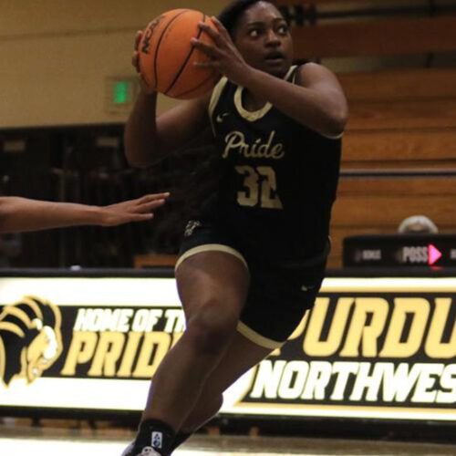 Female basketball player from Purdue University Northwest carries basketball in hand.