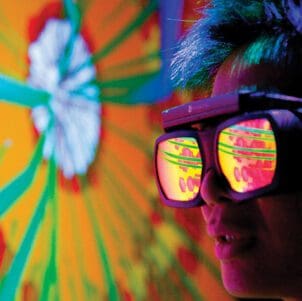 A person wearing reflective goggles looks at a blast furnace simulation