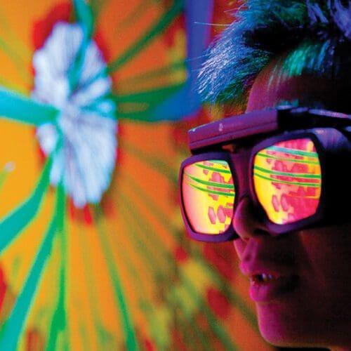 A person wearing reflective goggles looks at a blast furnace simulation