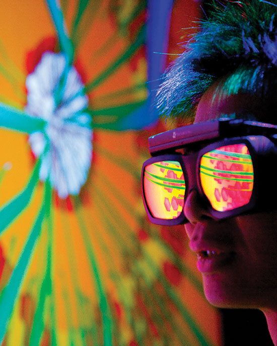 A person wearing reflective goggles looks at a blast furnace simulation