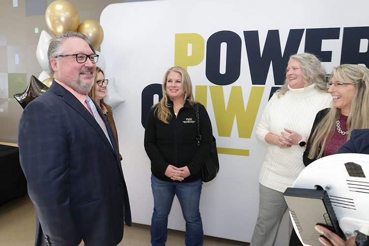 PNW Chancellor Chris Holford shares a laugh with fellow faculty and staff members as they pose for selfies with a Power Onward photo backdrop in Westville.