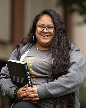 A PNW student poses with a psychology textbook