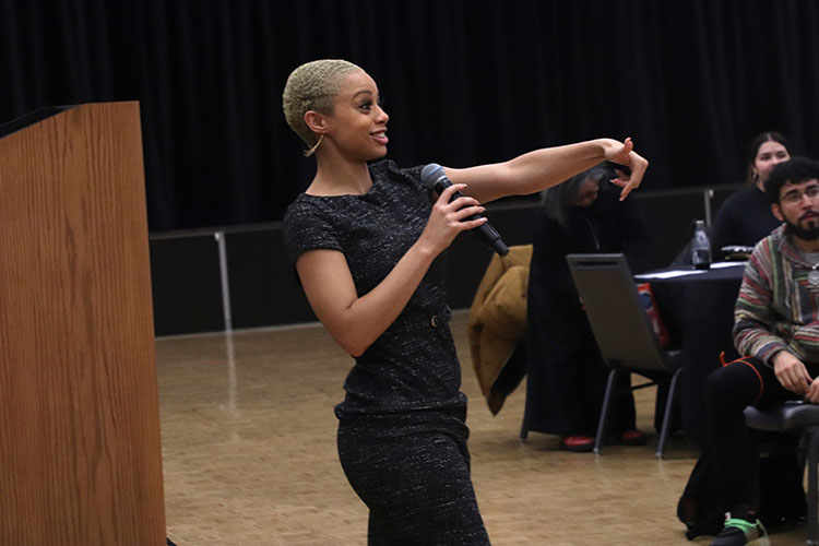 Darien Thompson walks in front of a stage holding a microphone.