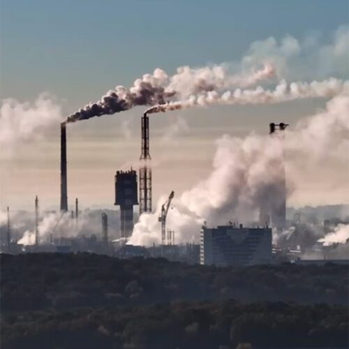 City skyline with smoke coming from industrial buildings, text over top "The Future of Steel, Decarbonizing with Hydrogen"