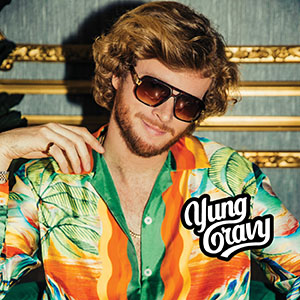 Yung Gravy sits in a silk tropical shirt and wears sunglasses. His logo is in the bottom right corner