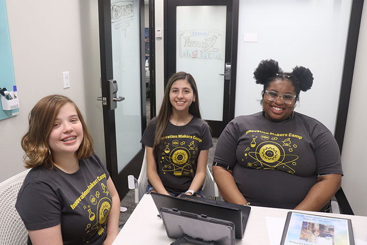 Three students sit together during a camp