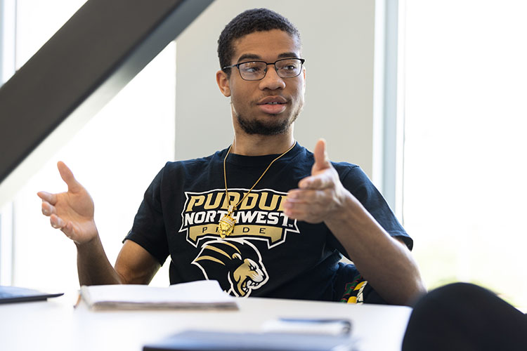 A student in a PNW Athletics t-shirt sits as a conference table