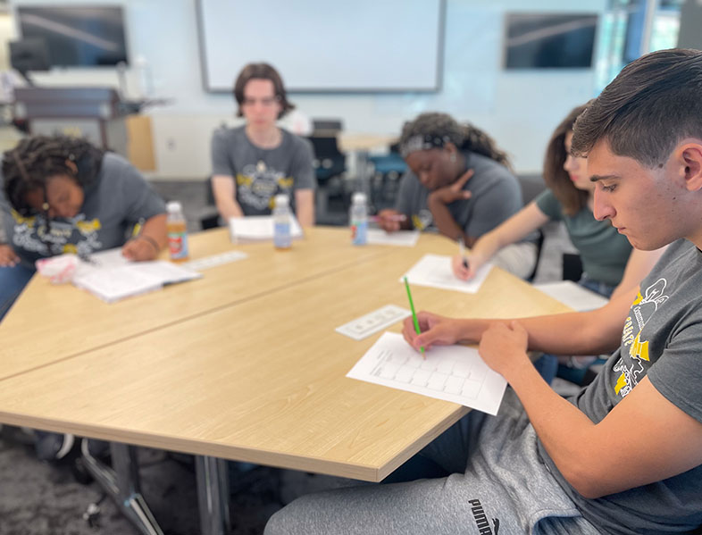 High school students sit around a table during a summer camp