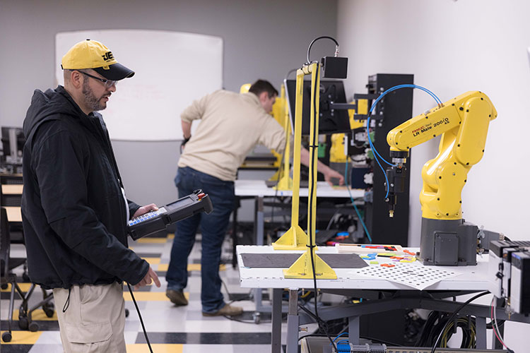 Students hold tablets and work on robots