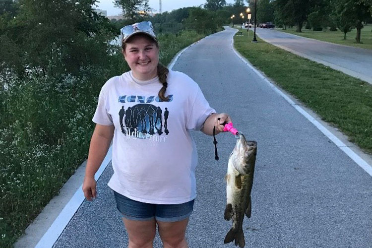 Woman holds up fish caught on fishing hook