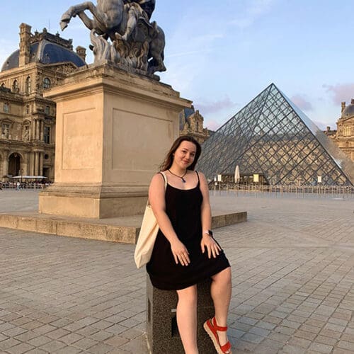 A PNW student sits in front of the Louvre.