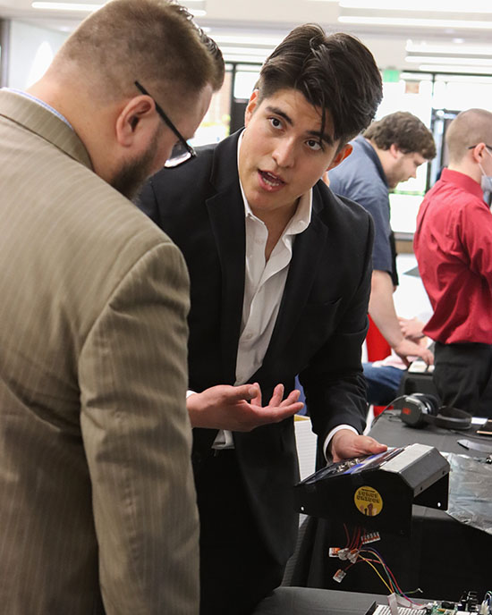 A man in a suit demonstrates an electronic device
