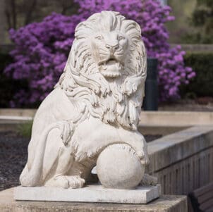 A PNW Lion statue with purple flowers blooming behind it