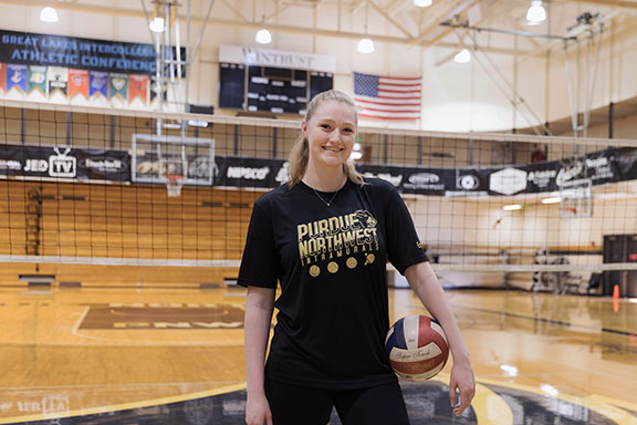 A student poses with a volleyball in a PNW intramurals shirt