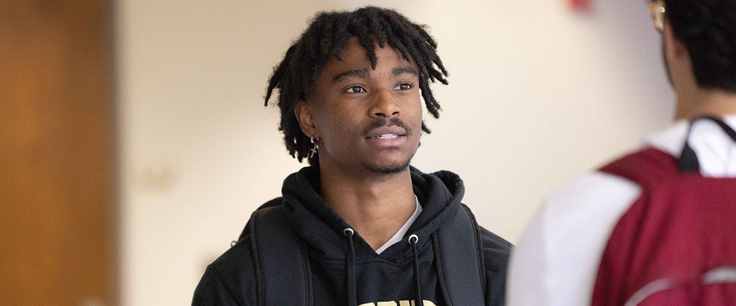 A student in a black hoodie talks to a student off camera