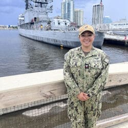 Alyssa Gomezdelacasa stands in uniform in front of a port
