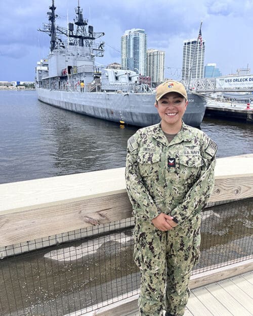 Alyssa Gomezdelacasa stands in uniform in front of a port
