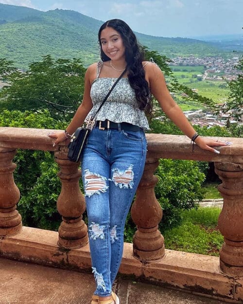 PNW student Fatima Chavez leans against a stone railing in front of a scenic view