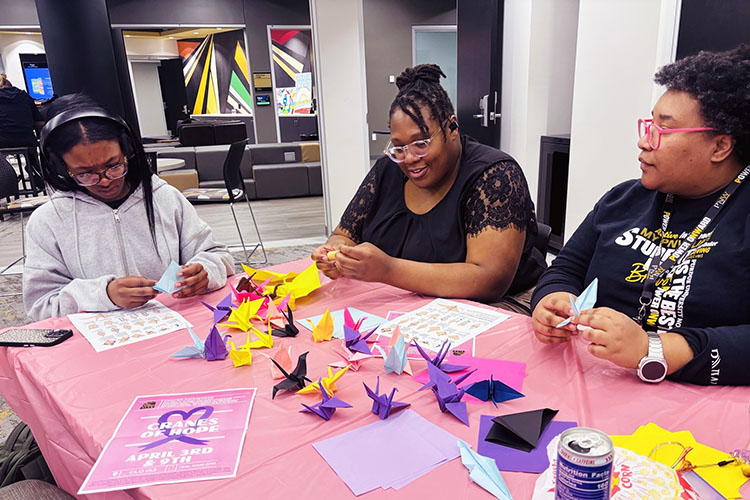 PNW student leaders fold cranes at a table