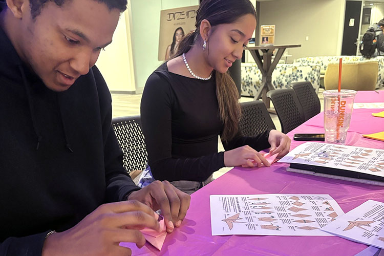 PNW student leaders fold cranes at a table