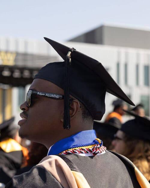 Terrell Sucre stands outside in commencement regalia