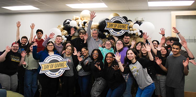 A group of people smiling and posing with colorful balloons at Purdue Northwest Day of Giving.