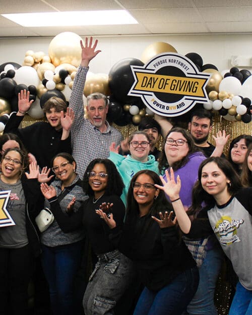 A group of people smiling and posing with colorful balloons at Purdue Northwest Day of Giving.