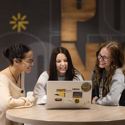 Three students sit around a table in the PNW Mane Zone
