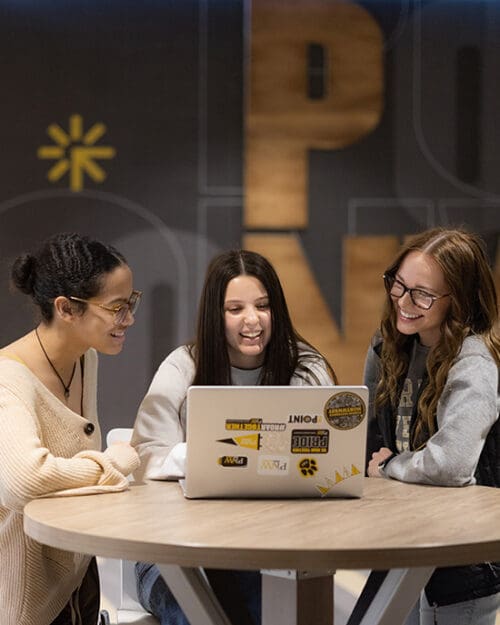 Three students sit around a table in the PNW Mane Zone