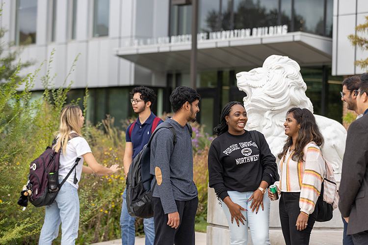 Seven students stand together outside of the Nils building
