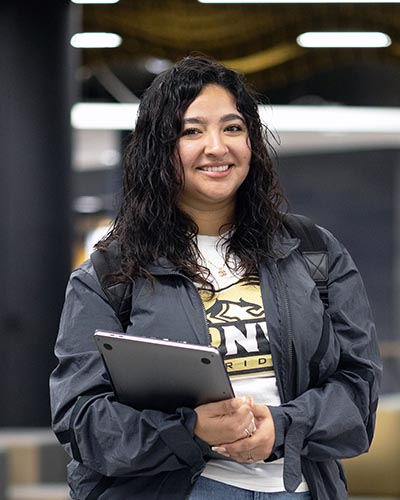 A PNW student holds books on campus