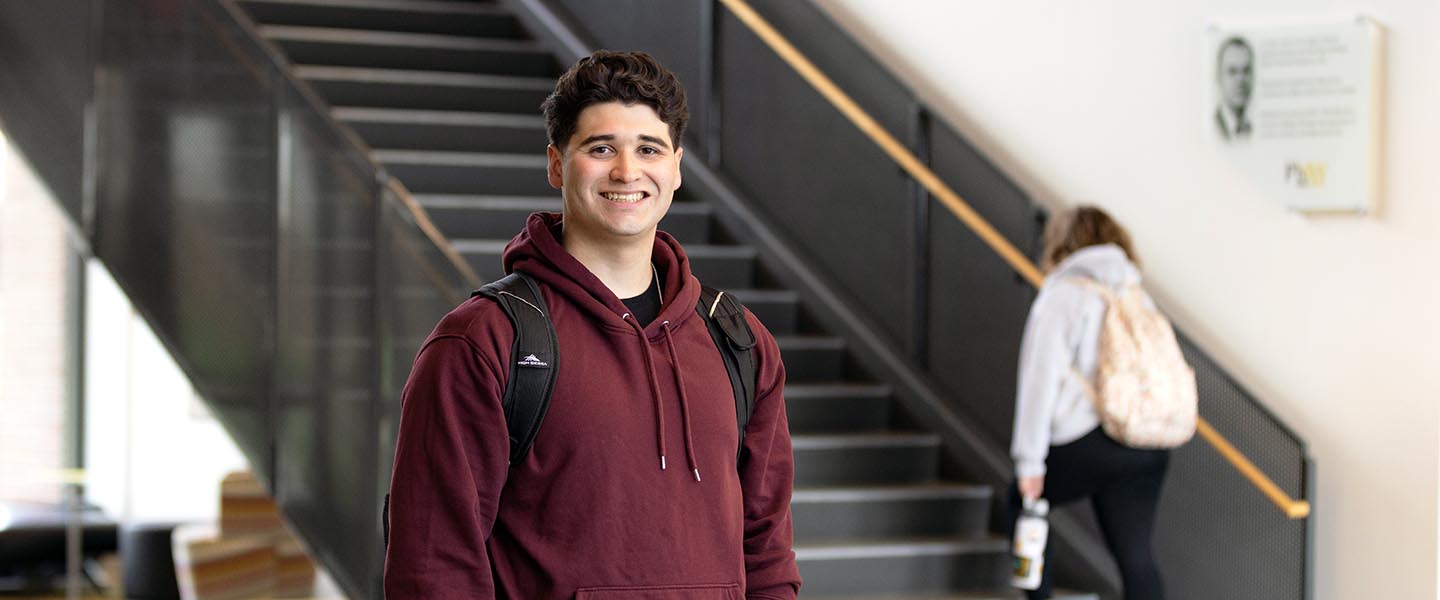 A PNW student stands in front of a stairwell