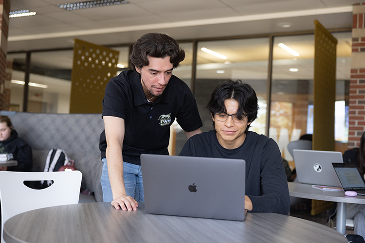 Two people looking at a laptop in the student lounge