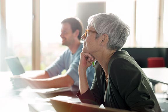 An older woman and man sit in a sunny classroom