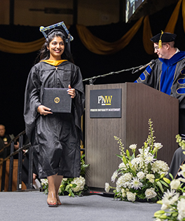 Student walking across the stage at 2024 commencement