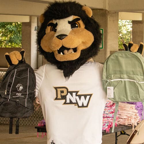 PNW Mascot Leo the Lion holds up two backpacks